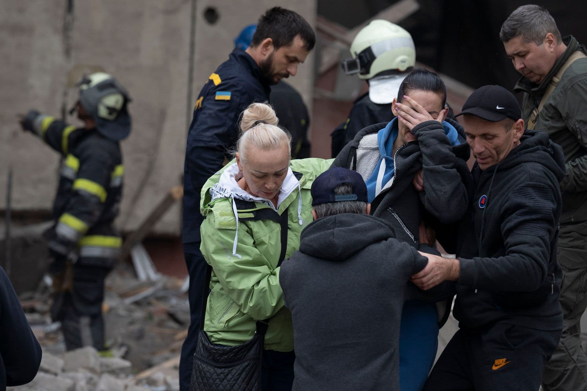 Relatives and friends comfort a woman after Ukrainian rescue workers found a body of a person under the debris following a Russian attack that heavily damaged a school in Mykolaivka