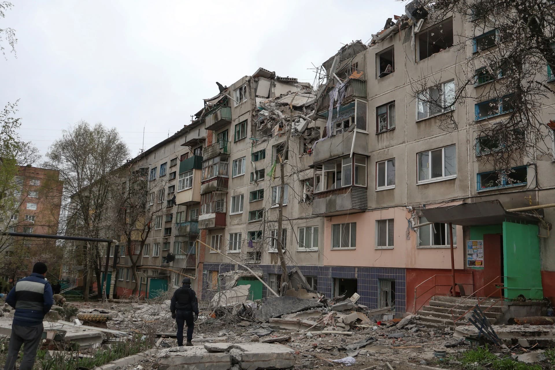 People look at a building damaged by a Russian rocket attack in Sloviansk