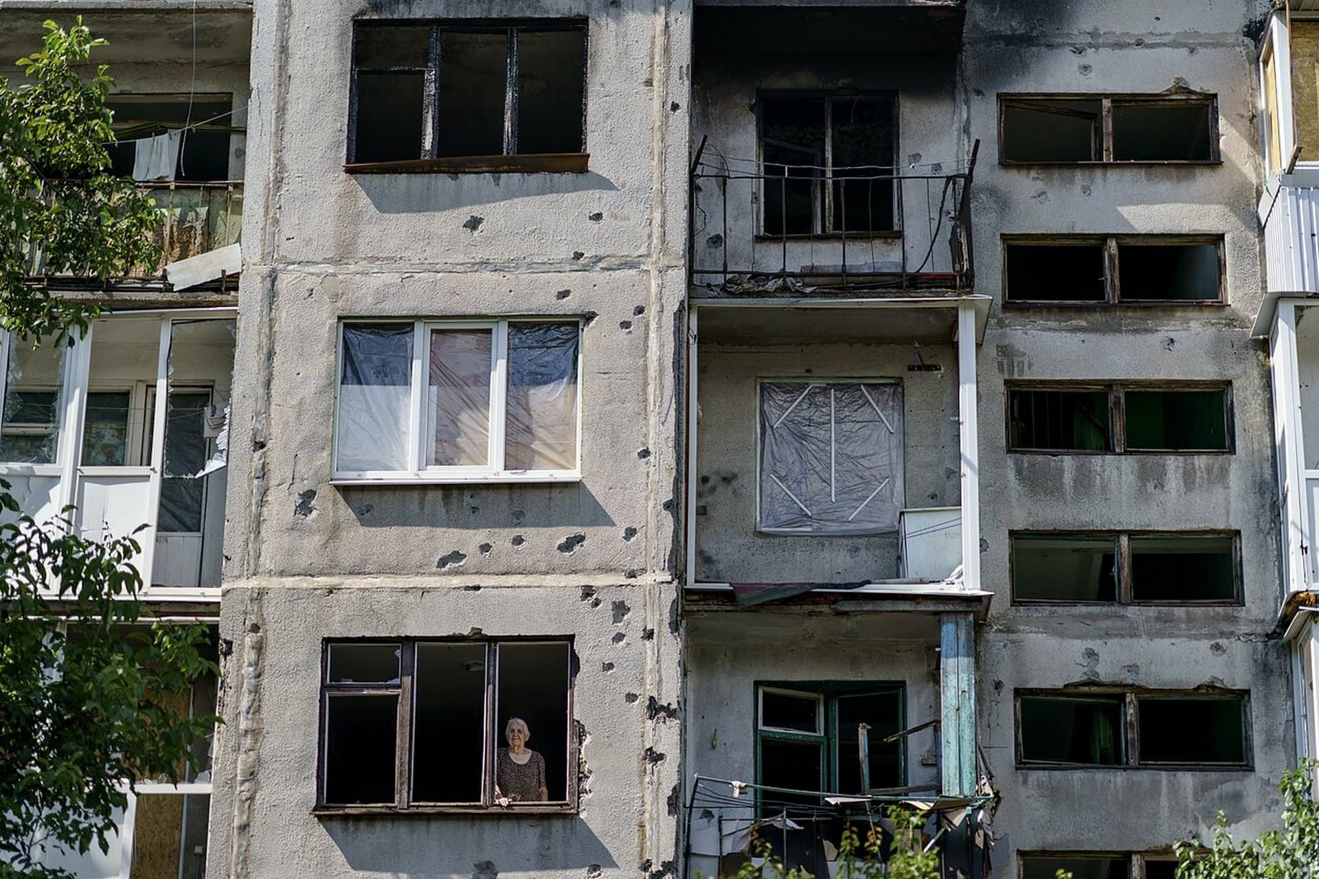 Ida Svystunova, 89, looks out the damaged room adjoining her apartment from a May rocket attack in Sloviansk