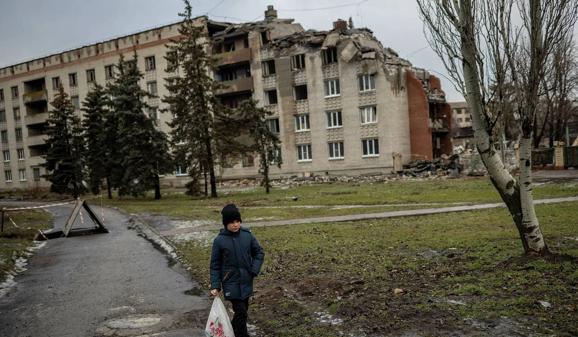 A boy walks past a building damaged by shelling in Sloviansk