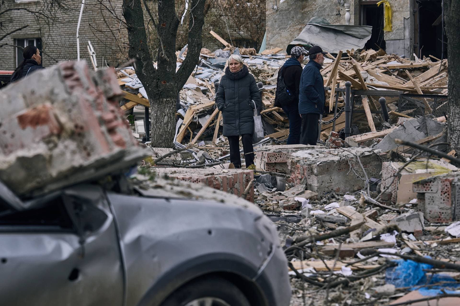 People stand in front of a heavily damaged building after a Russian attack in Sloviansk