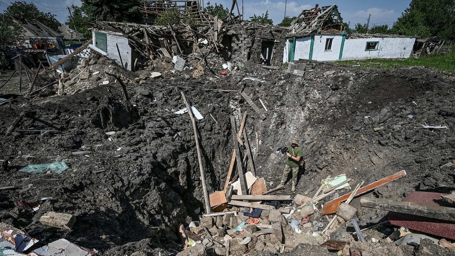 A Ukrainian service member stands inside a crater next to a residential house destroyed by yesterday's Russian military strike in Chaplyne