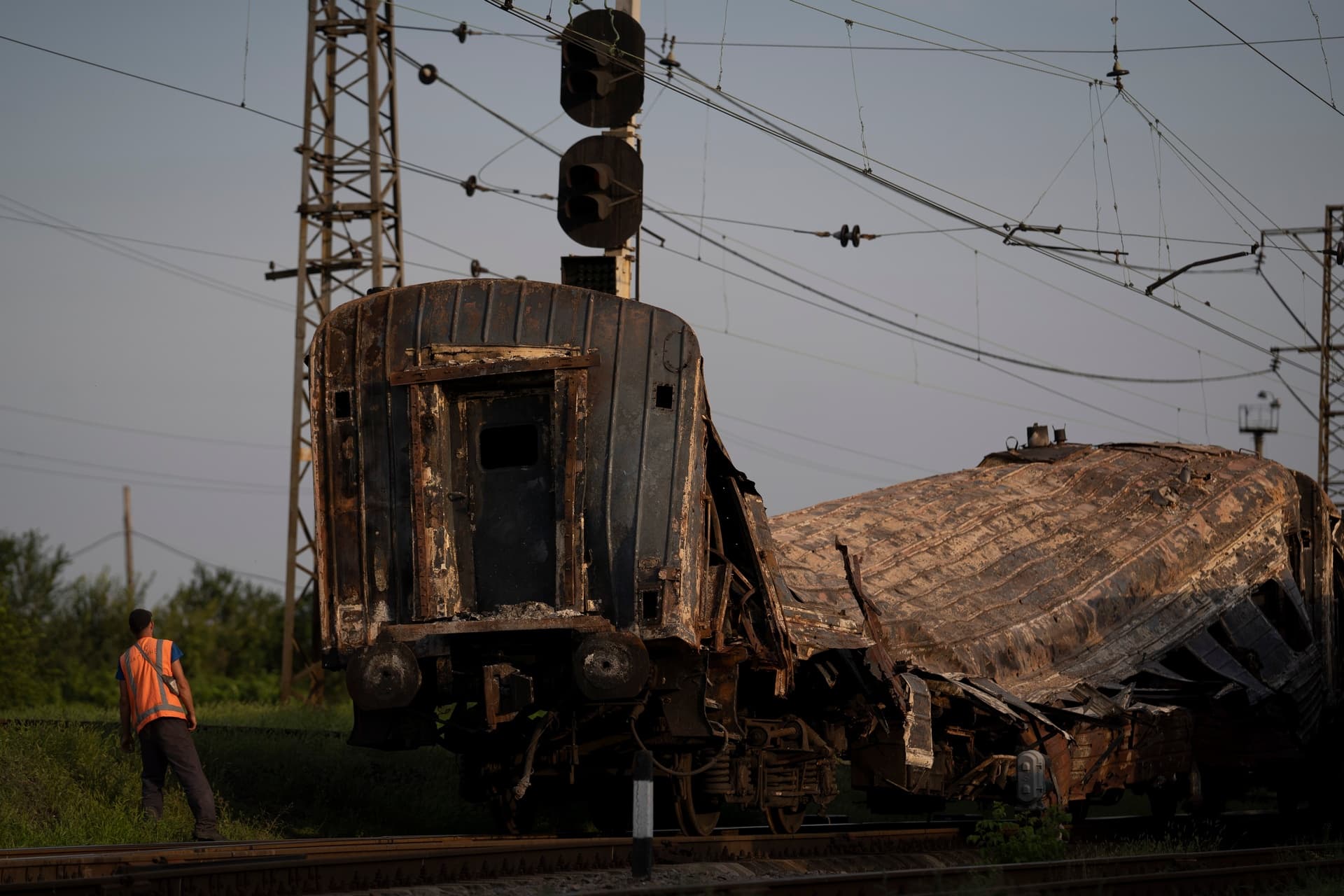 A railway worker looks at a heavily damaged train after a Russian attack on a train station Wednesday during Ukraine's Independence Day in the village Chaplyne