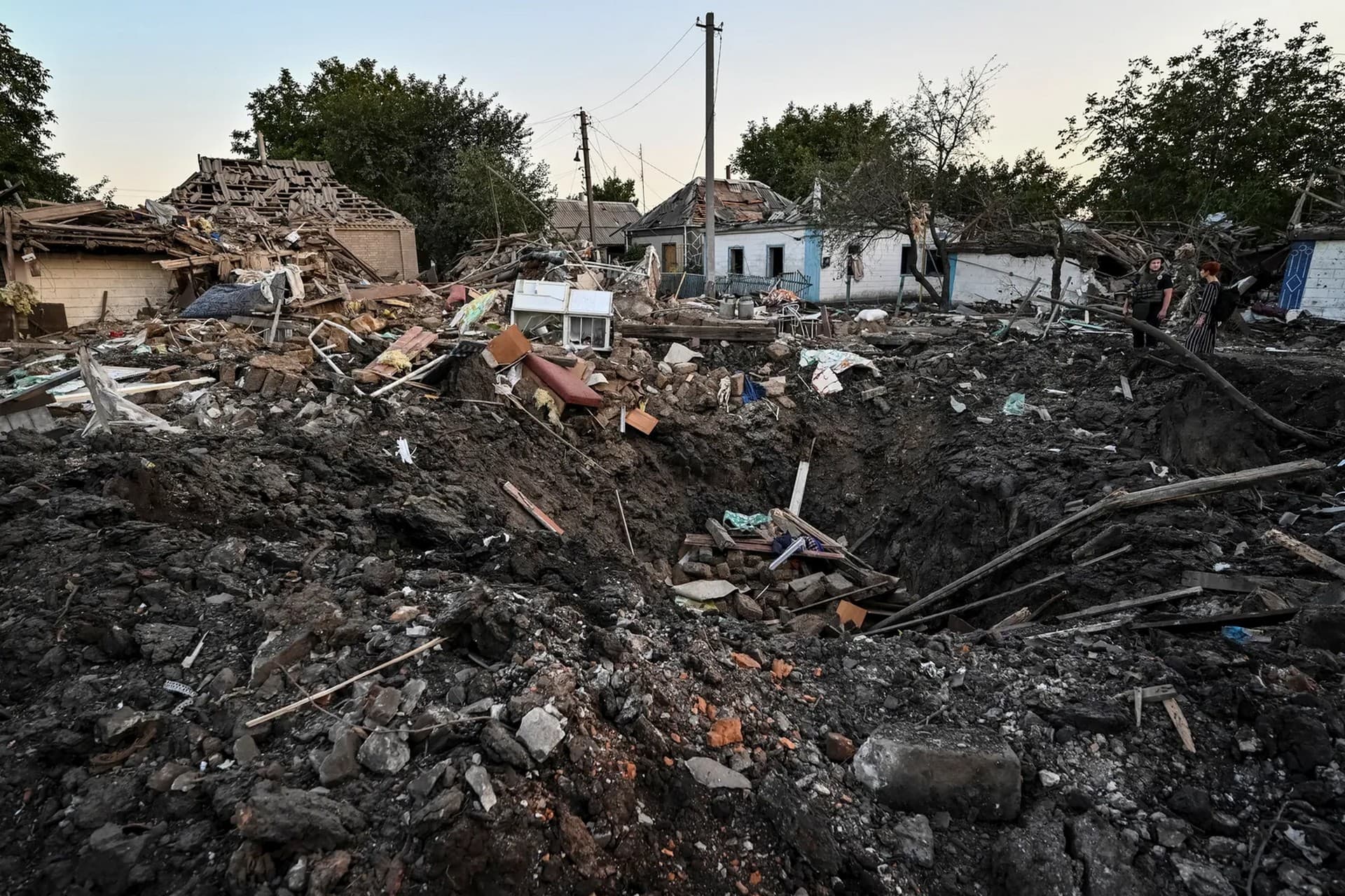 People stand next to a residential house destroyed by a Russian military raid, as Russia's attack on Ukraine continues, in Chaplyne