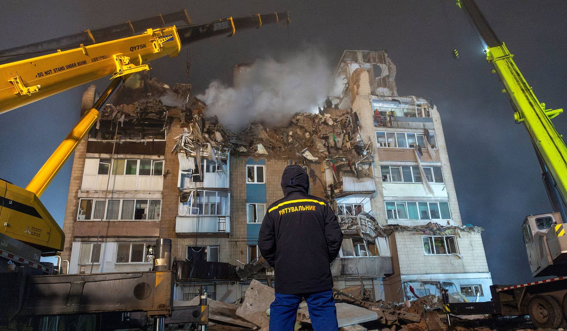 An emergency responder stands in front of an apartment building that was hit yesterday by a Russian missile in Ternopil