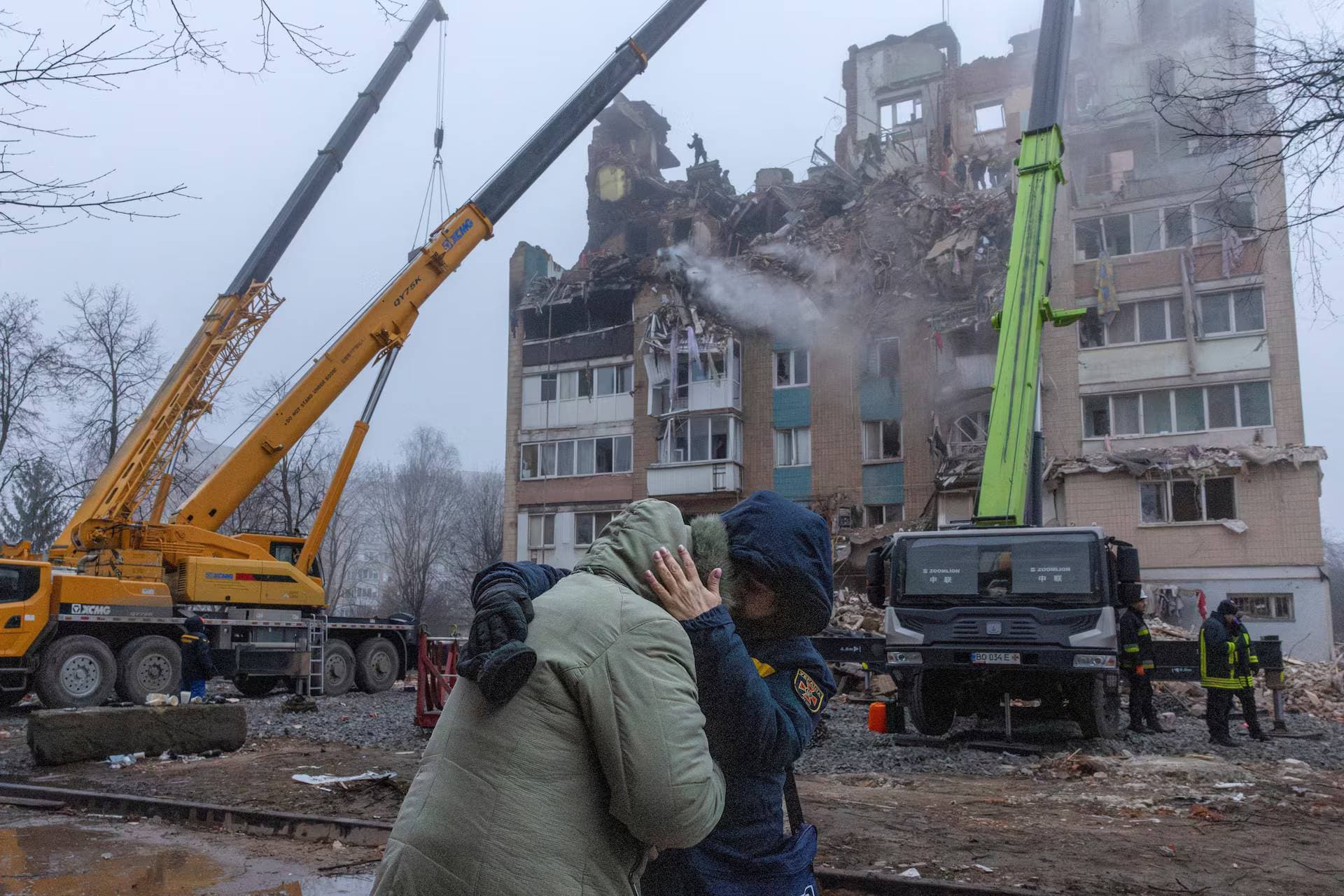 A psychologist comforts a resident in front of an apartment building that was hit yesterday by a Russian missile in Ternopil