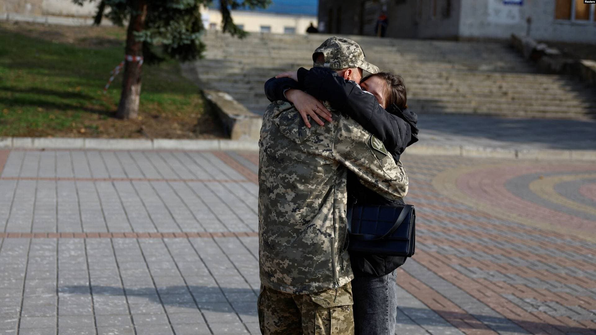 an Ukrainian soldier hugs his daughter in a front of a railway station in Trostyanets