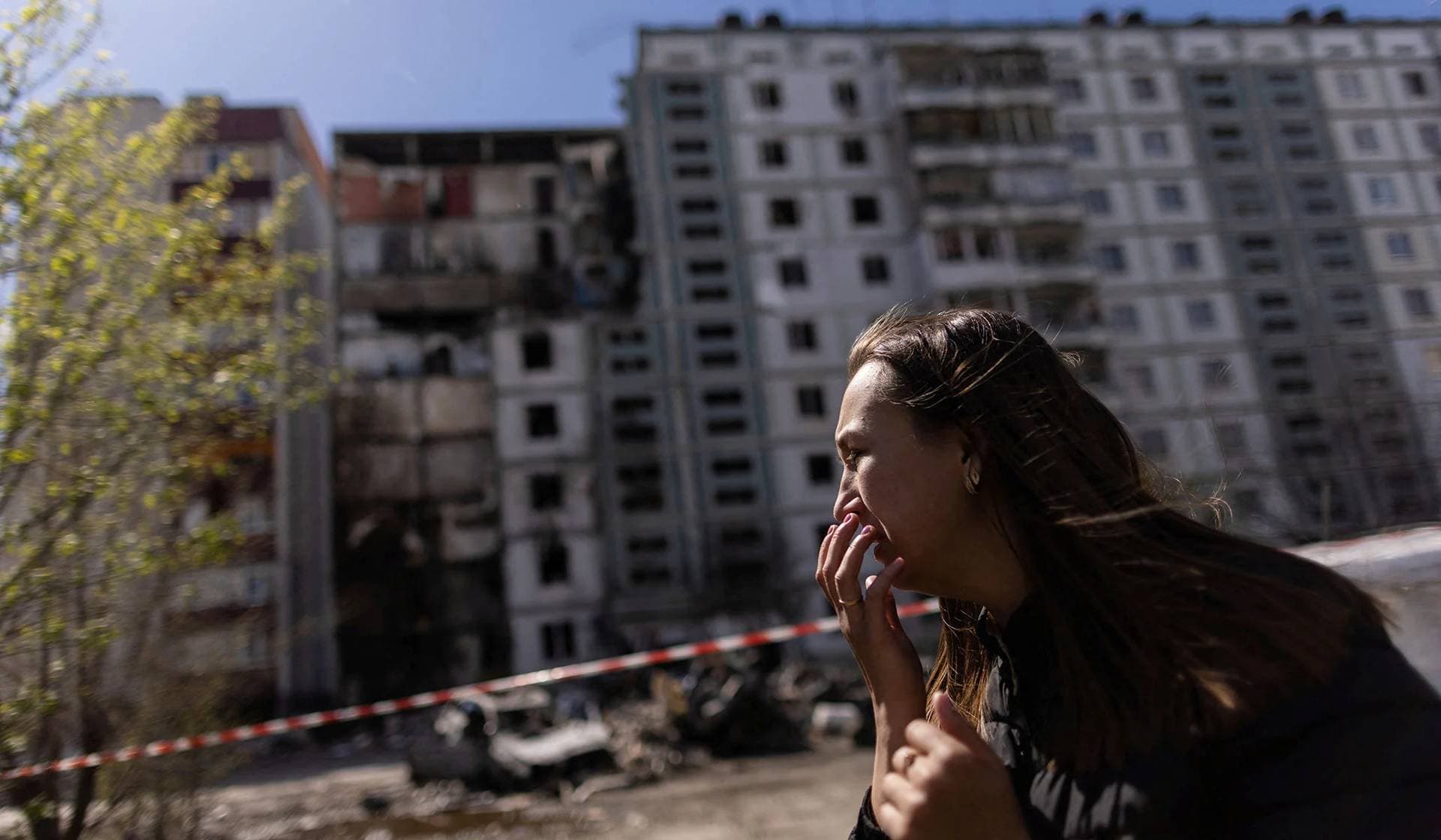 A woman reacts as she pays tribute to civilian people killed yesterday by a Russian missile strike in Uman