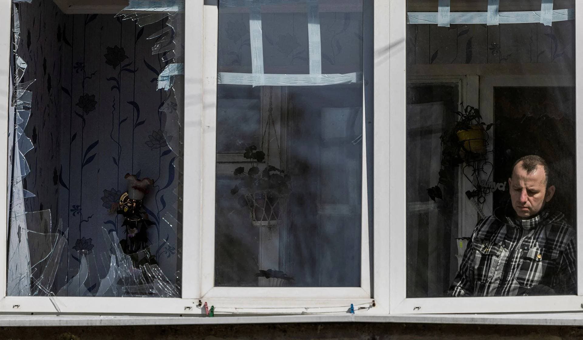 A local resident looks out of a window of a damaged residential building hit by a Russian missile in Uman