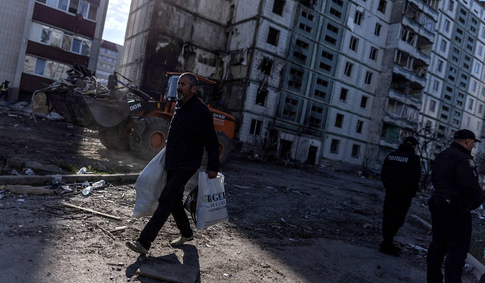 A local resident walks out of his damaged apartment with belongings after a Russian missile strike in Uman