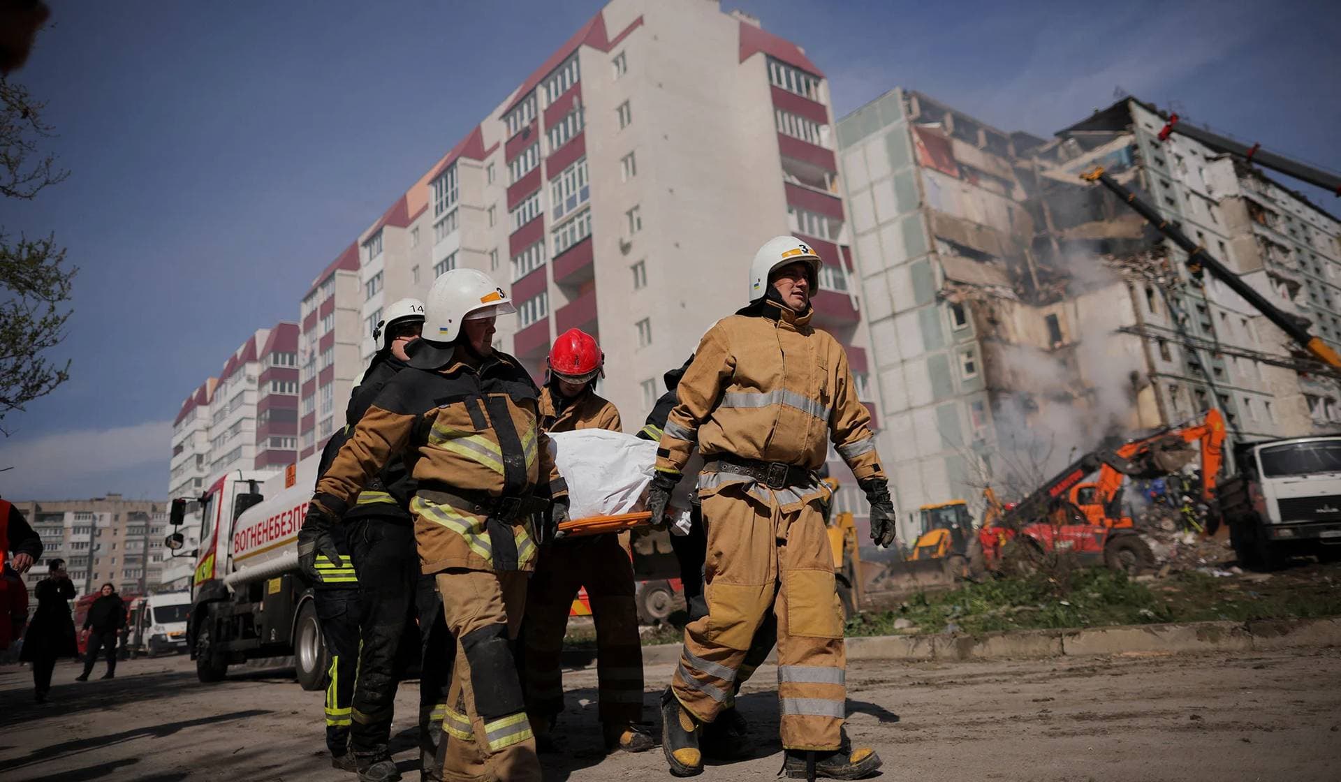 Rescuers carry a body covered with a bag as they work at the site of a heavily damaged residential building hit by a Russian missile in Uman
