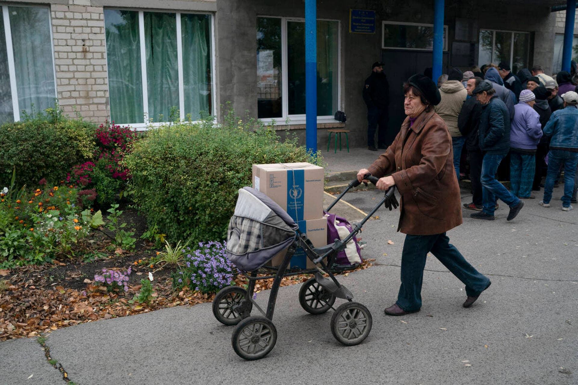 A woman pushes a baby cart loaded with boxes as humanitarian aid is distributed at the village of Mykhailo Lukasheve