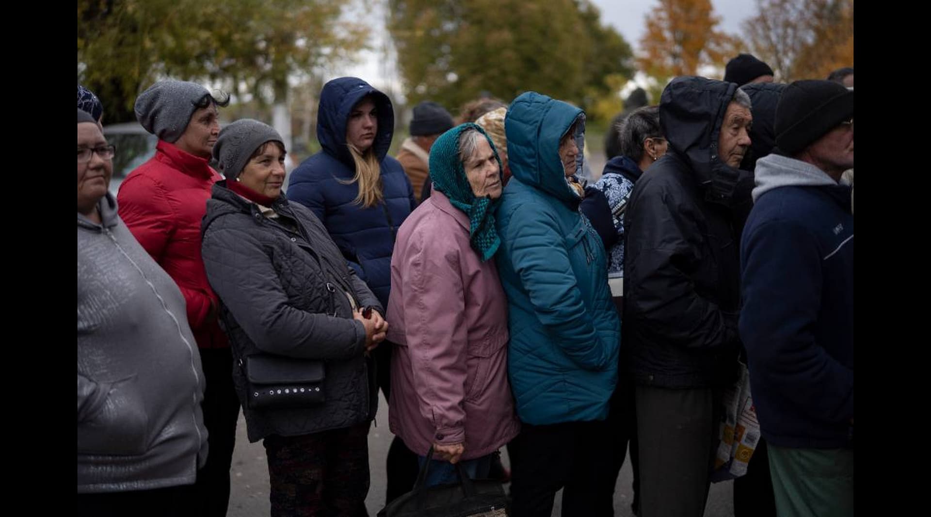 People wait in line as humanitarian aid is distributed at the village of Mykhailo Lukasheve