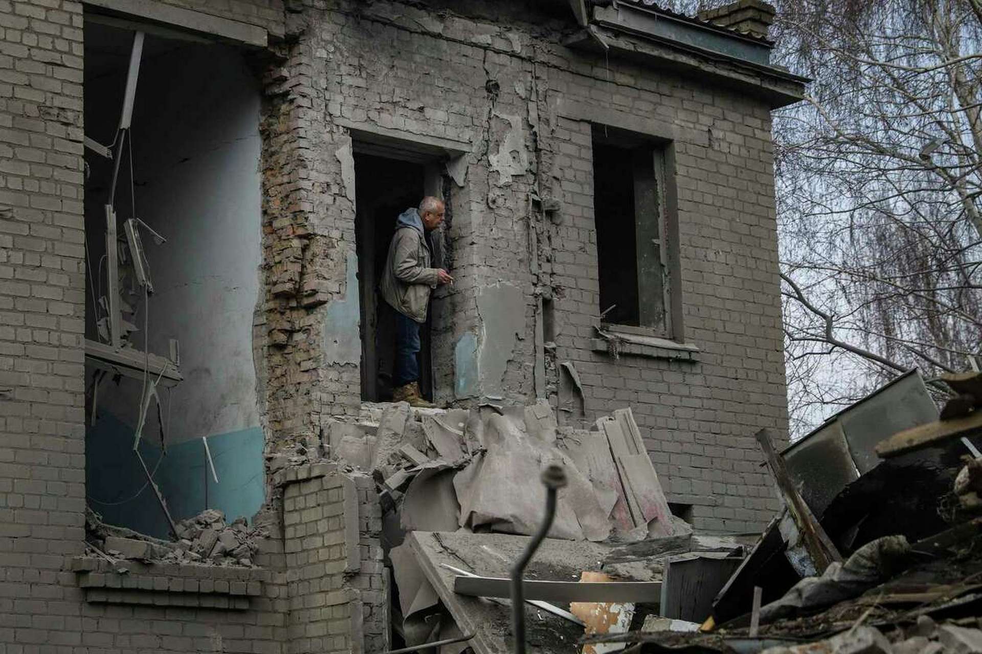 A man looks out of a damaged maternity hospital in Vilniansk
