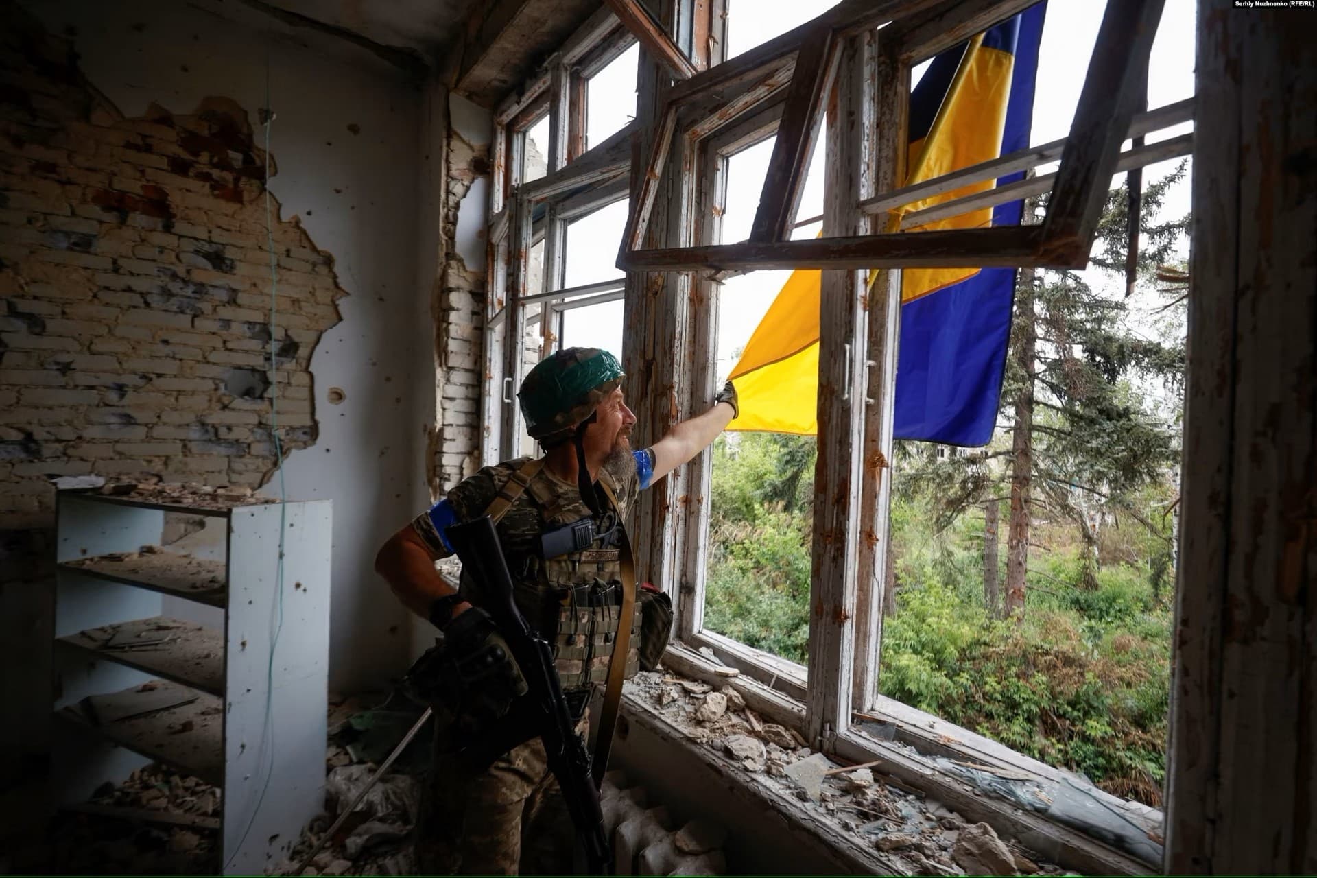 A Ukrainian soldier on June 17 straightens his country's national flag, which was hung from the House of Culture in the newly liberated village of Blahodatne