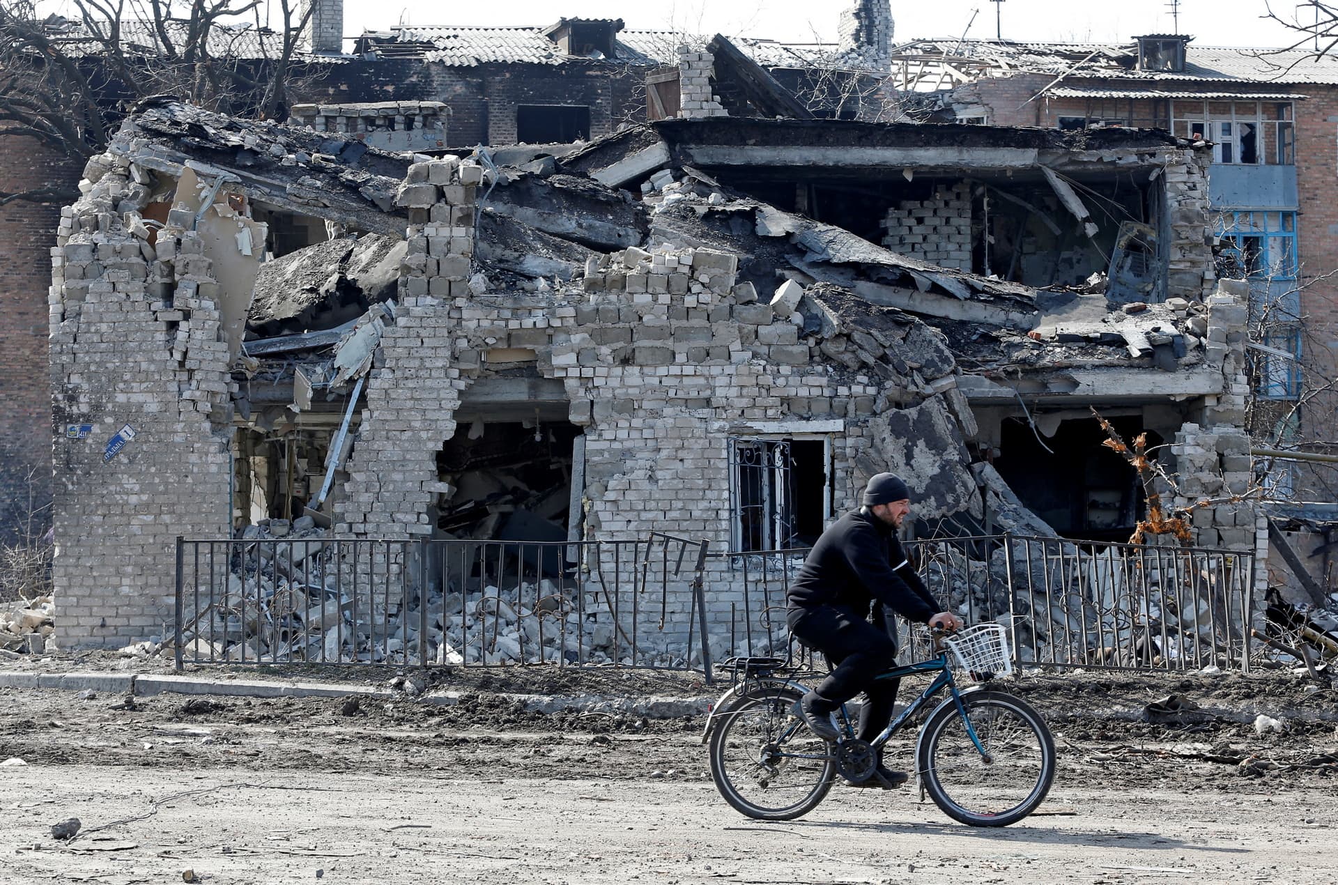 A local resident rides a bicycle past a building destroyed during Ukraine-Russia conflict in the separatist-controlled town of Volnovakha in the Donetsk region, Ukraine.