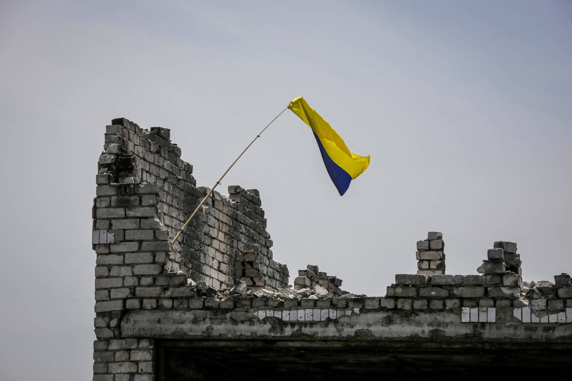 The Ukrainian national flag above the rubble of a destroyed home in the newly liberated village of Neskuchne