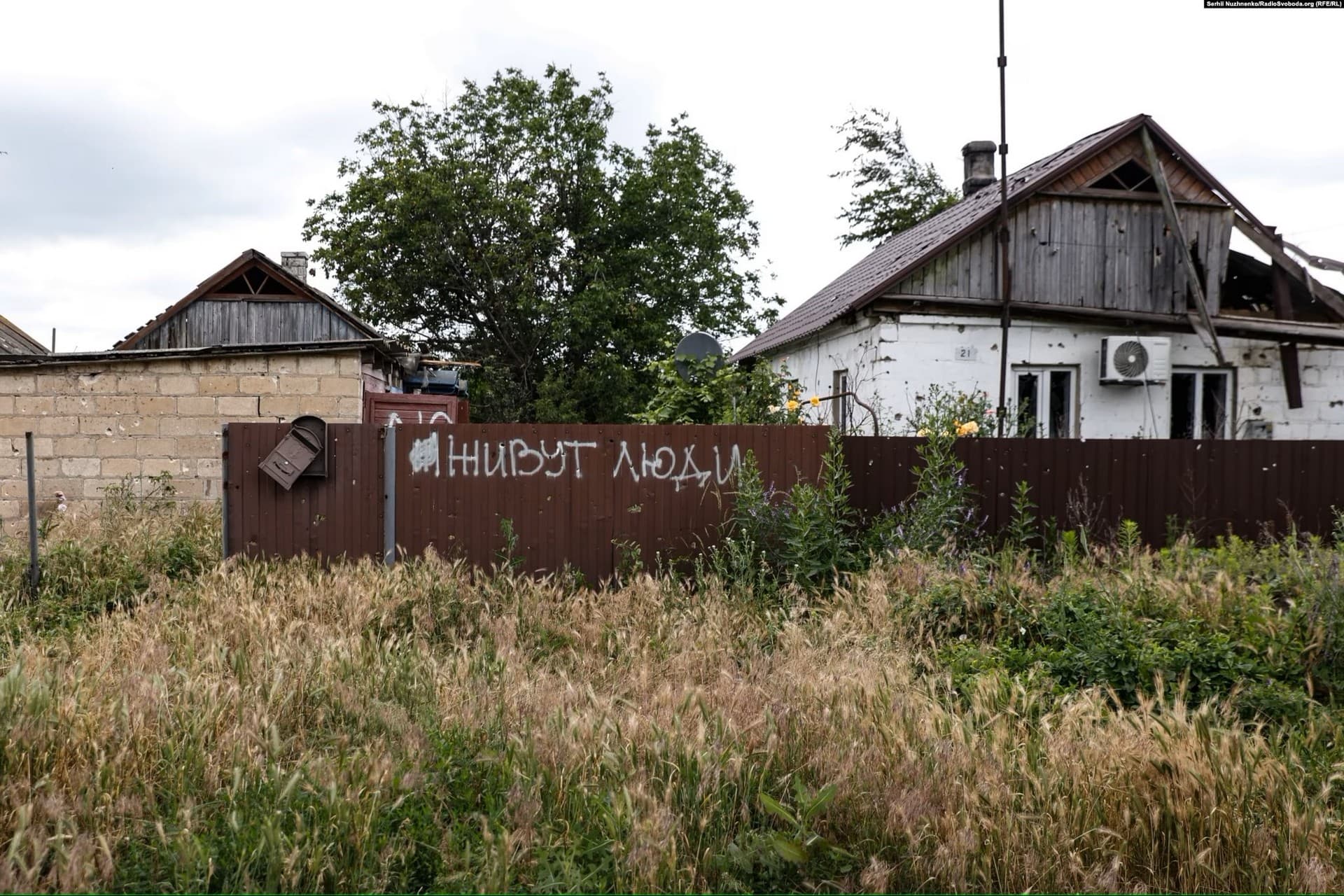 Graffiti on a fence in Blahodatne that roughly translates as 'People live here'