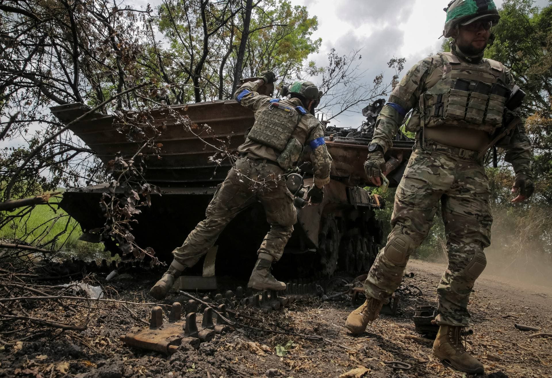 Ukrainian service members check a destroyed Russian a BMP-2 infantry fighting vehicle near the front line in the newly liberated village Storozheve