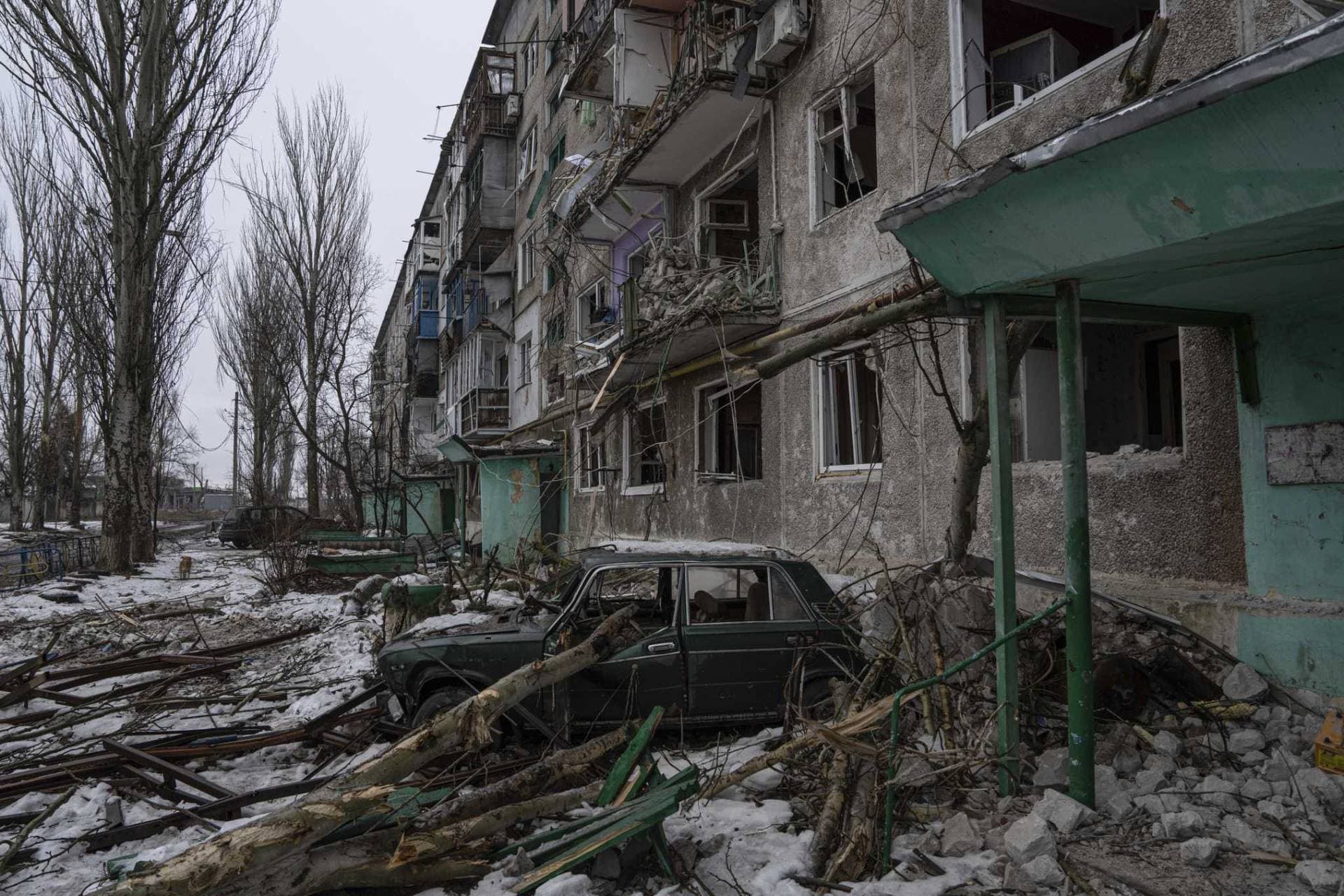 A destroyed car is seen in front of a residential building in the frontline city of Vuhledar
