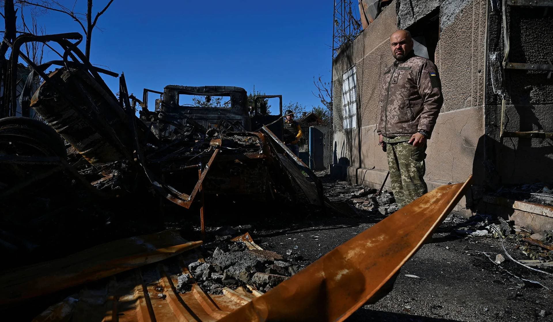 A Ukrainian serviceman stands next to a destroyed military vehicle in the village of Velyka Novosilka