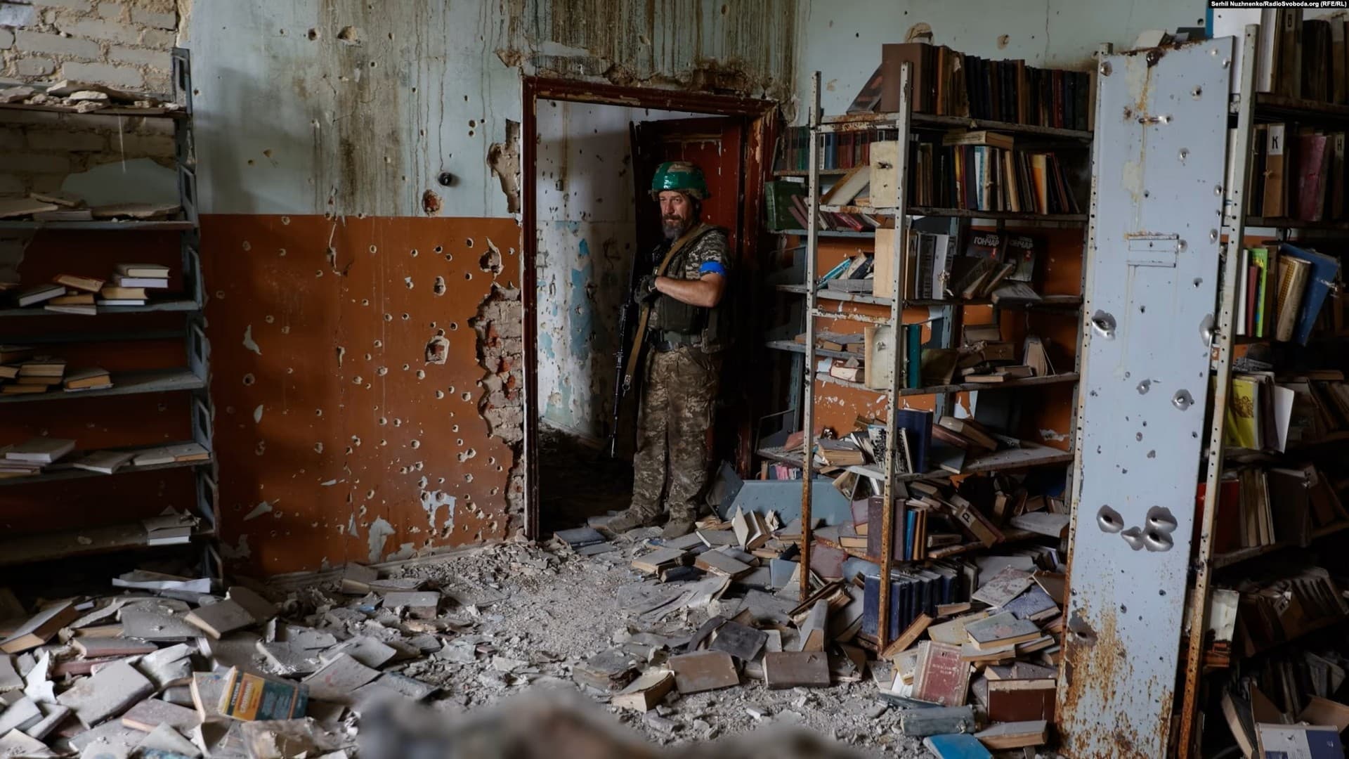 A Ukrainian soldier inspects a destroyed library in the newly liberated village of Blahodatne