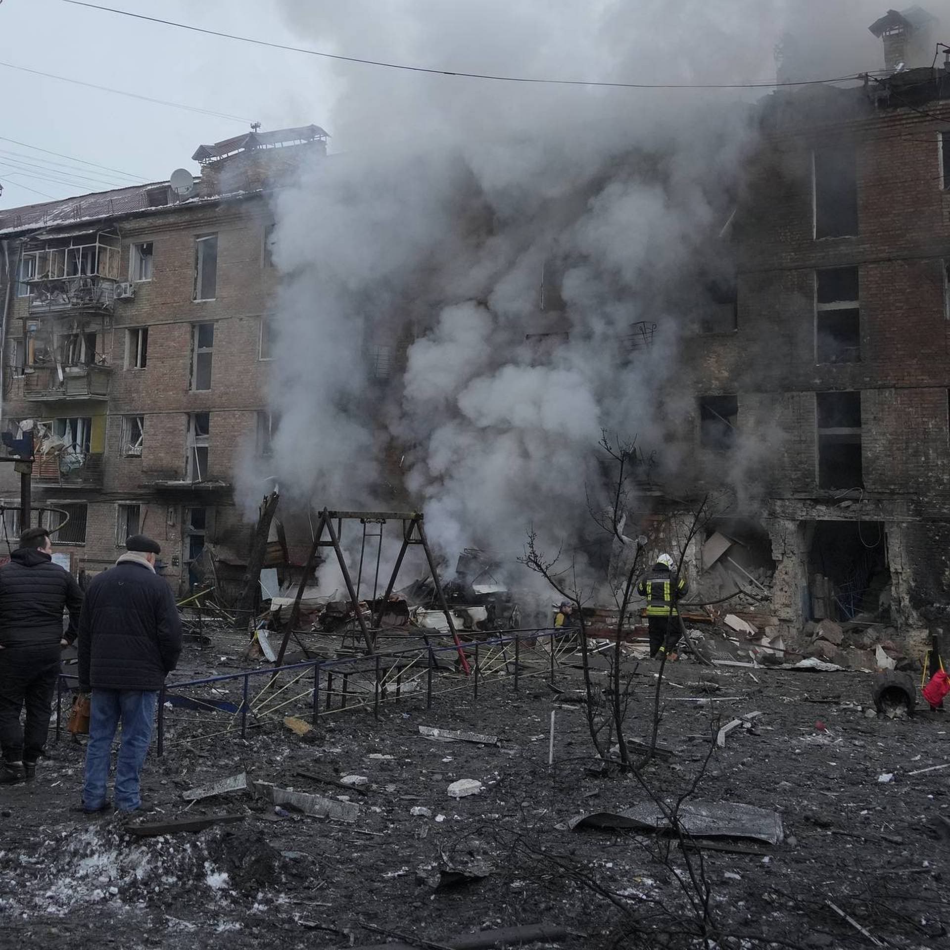 People check a damaged building as emergency personnel work at the scene of a Russian shelling in the town of Vyshgorod
