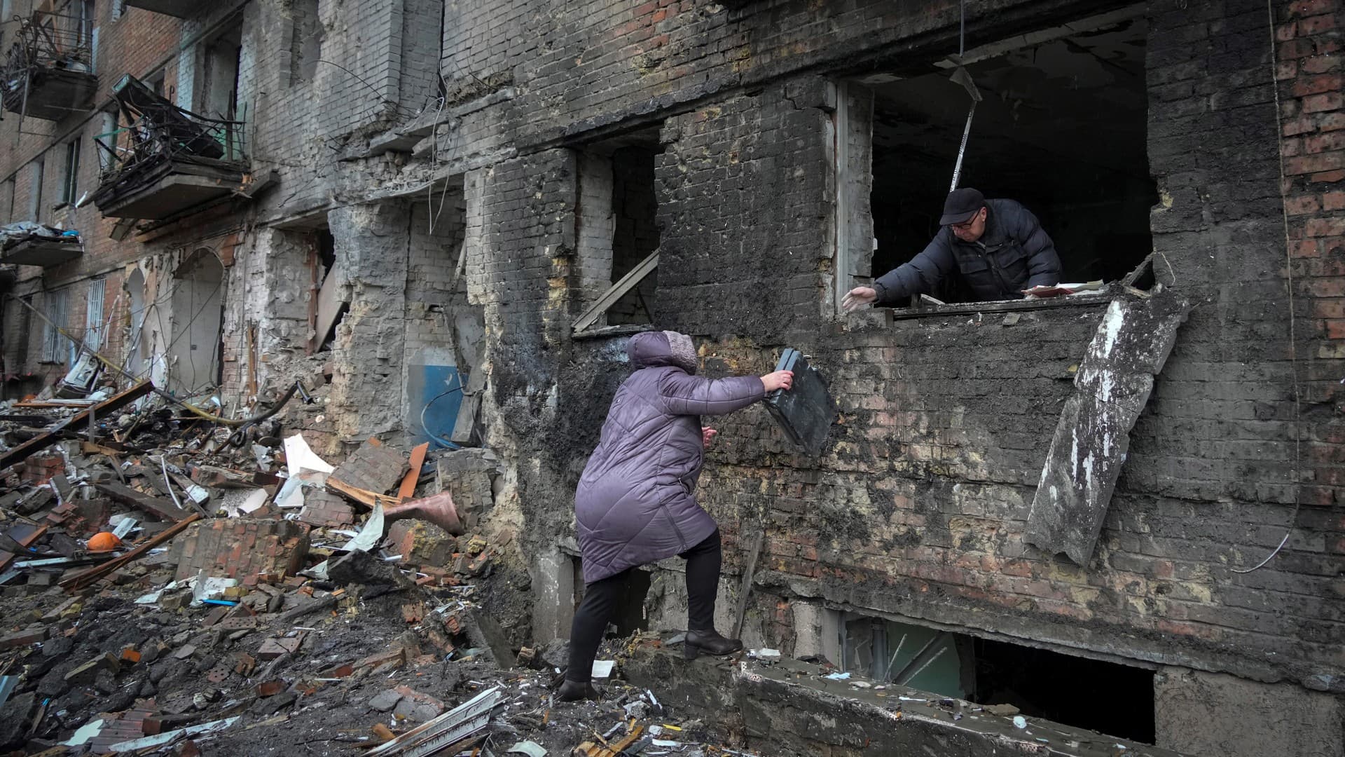 People gather their belongings from a damaged house after Russian shelling in the town of Vyshgorod