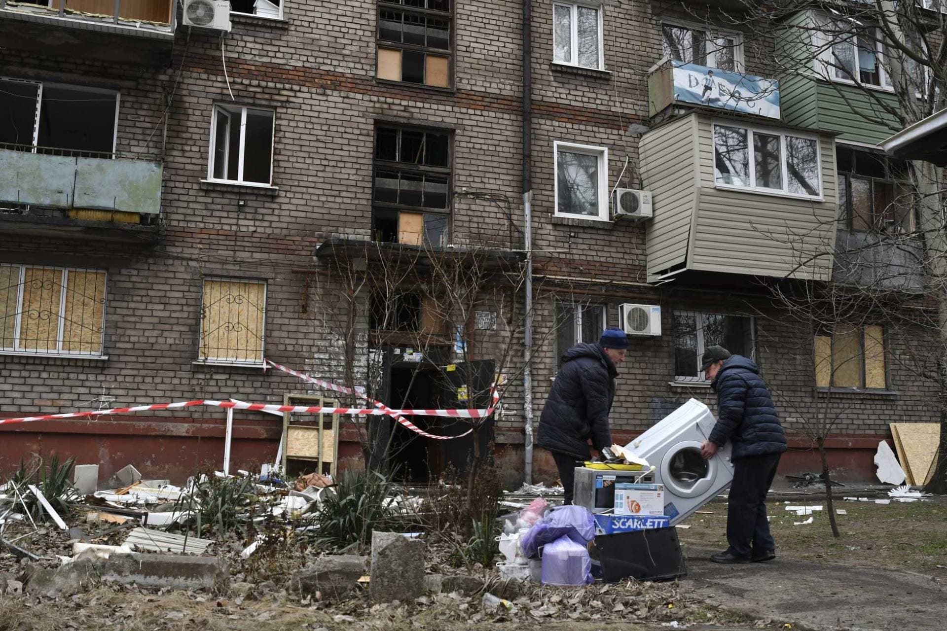 Local residents carry their belongings as they leave their home damaged in the night Russian rocket attack in Zaporizhzhya