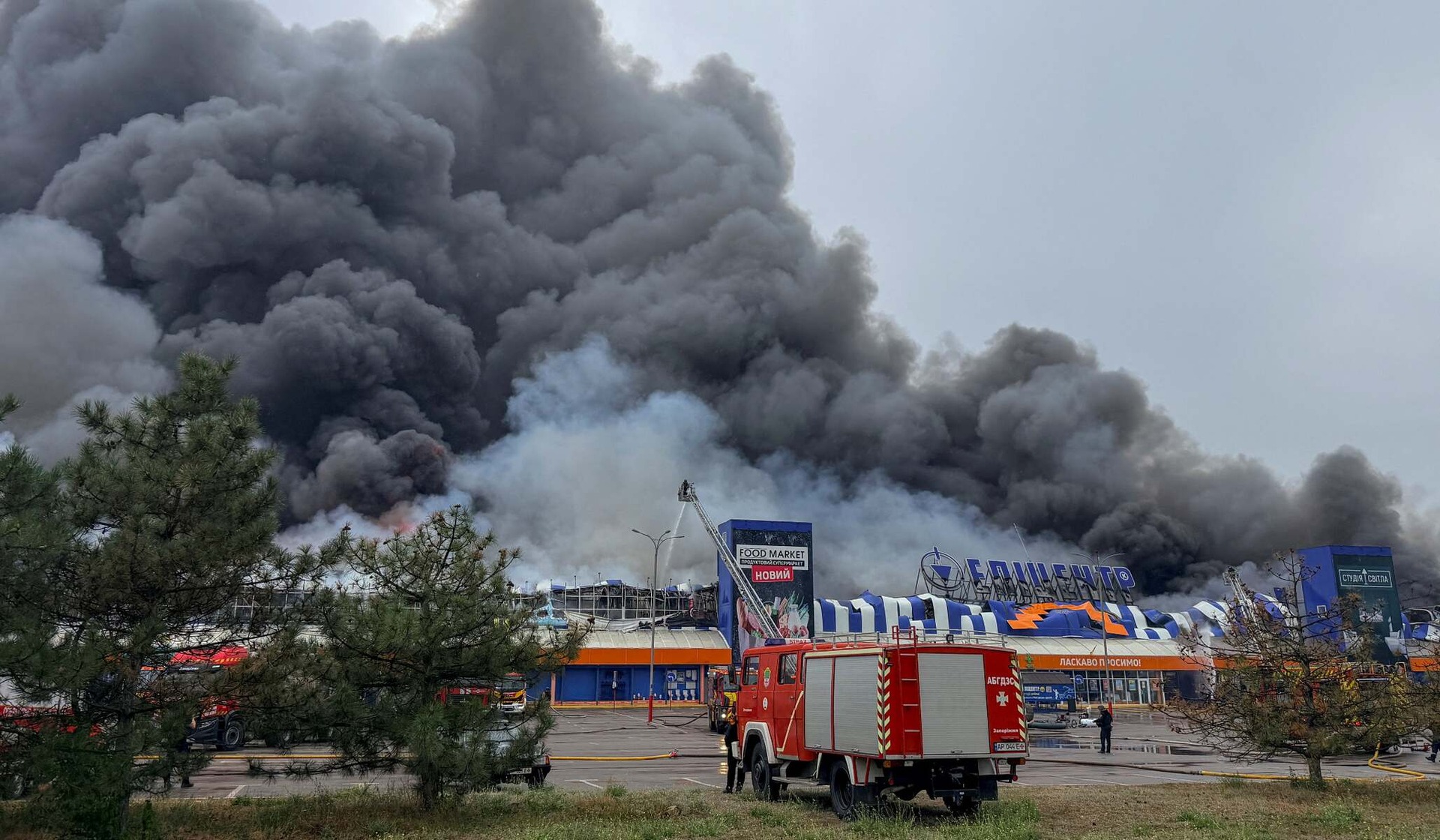 Firefighters work as smoke and flames rise from a home-improvement shopping center struck by Russian drones in Zaporizhzhia