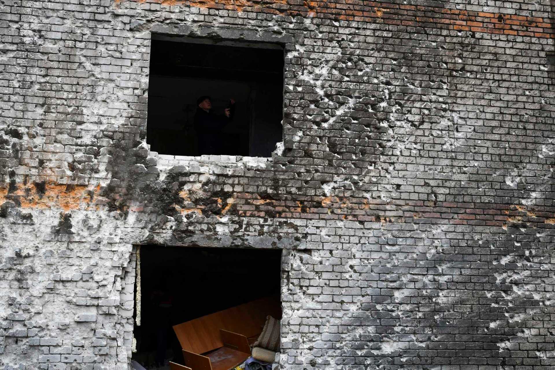A local resident is seen in a window hole of an apartment building damaged in the night following a Russian rocket attack in Zaporizhzhya