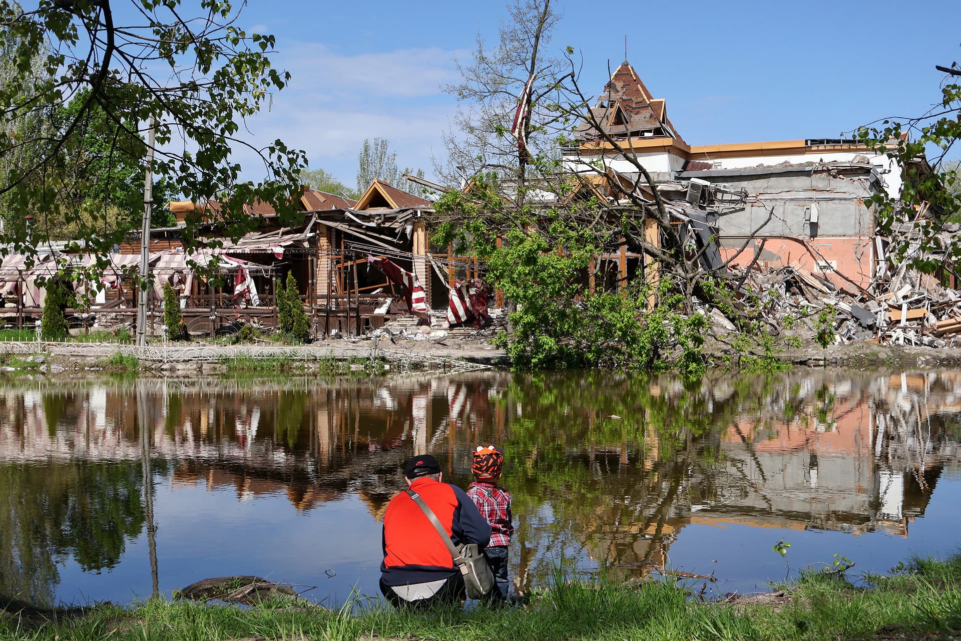 A man with a child walk past the destroyed Sunrise Park Hotel following Russian shelling, in Zaporizhia