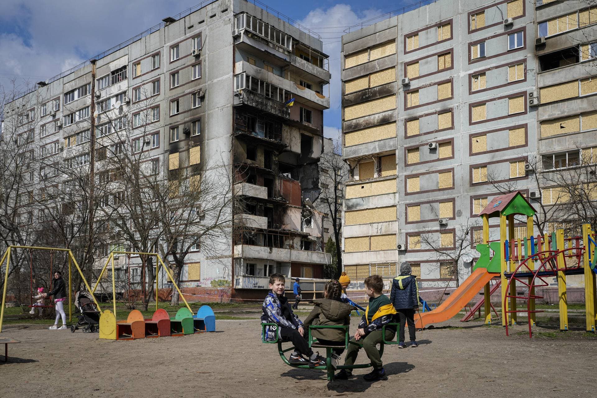 Children play in a playground in front of missile-damaged buildings in Zaporizhzhia