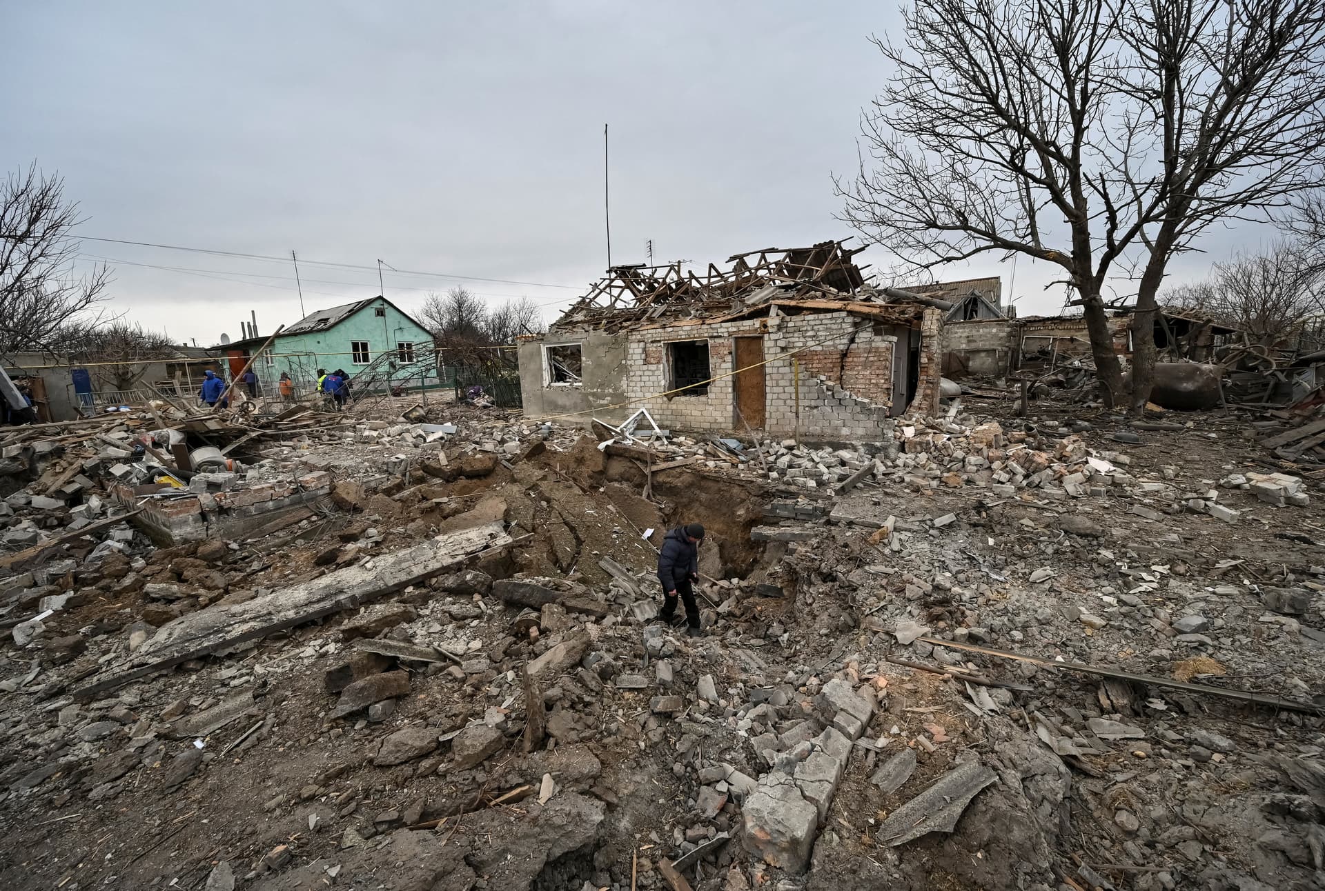 A local resident inspects a crater left by a Russian military strike in the village of Kupriianivka