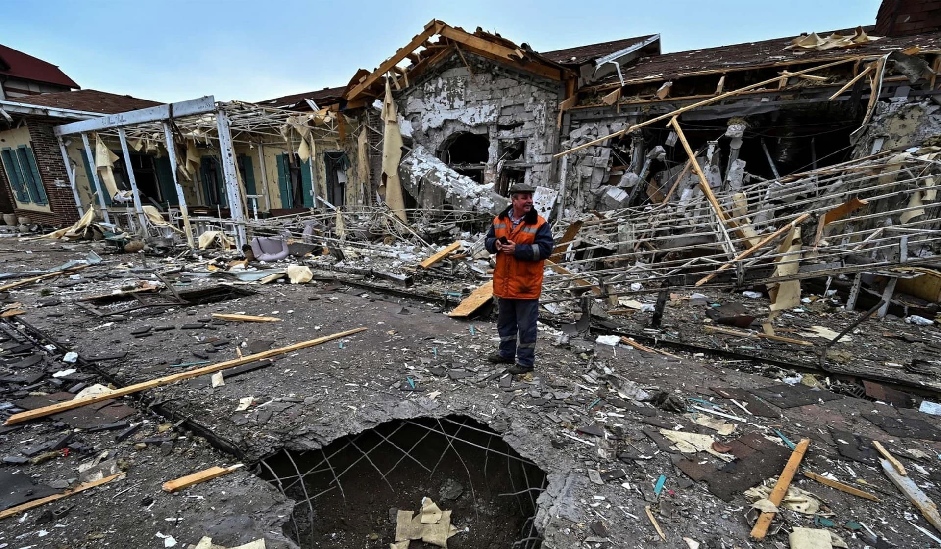 A municipal worker stands next to a building of a hotel and spa complex damaged by a Russian missile strike in Zaporizhzhia