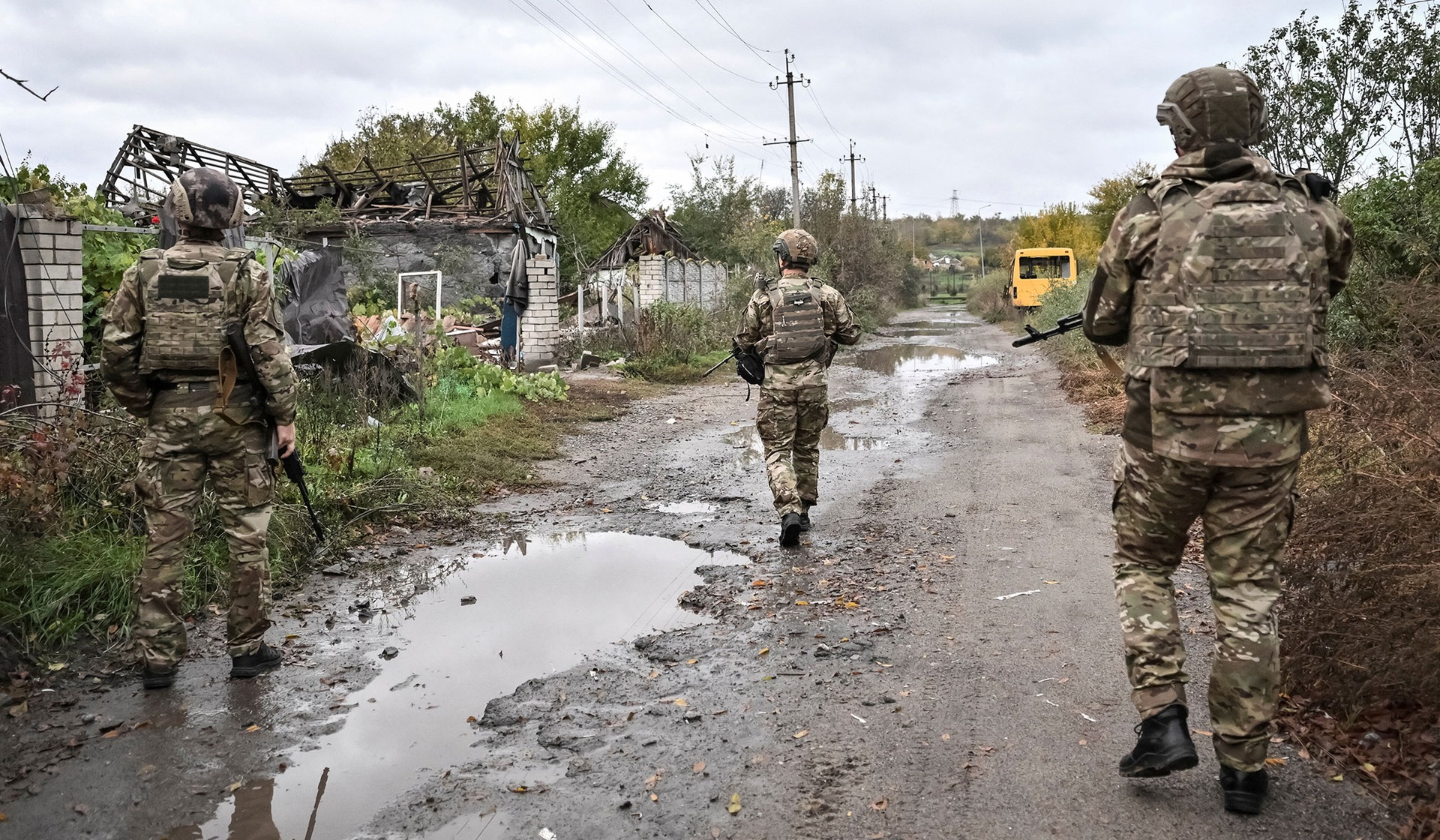 Police officers from the evacuation unit walk on a street during the evacuation mission in the frontline rural settlement Komyshuvakha