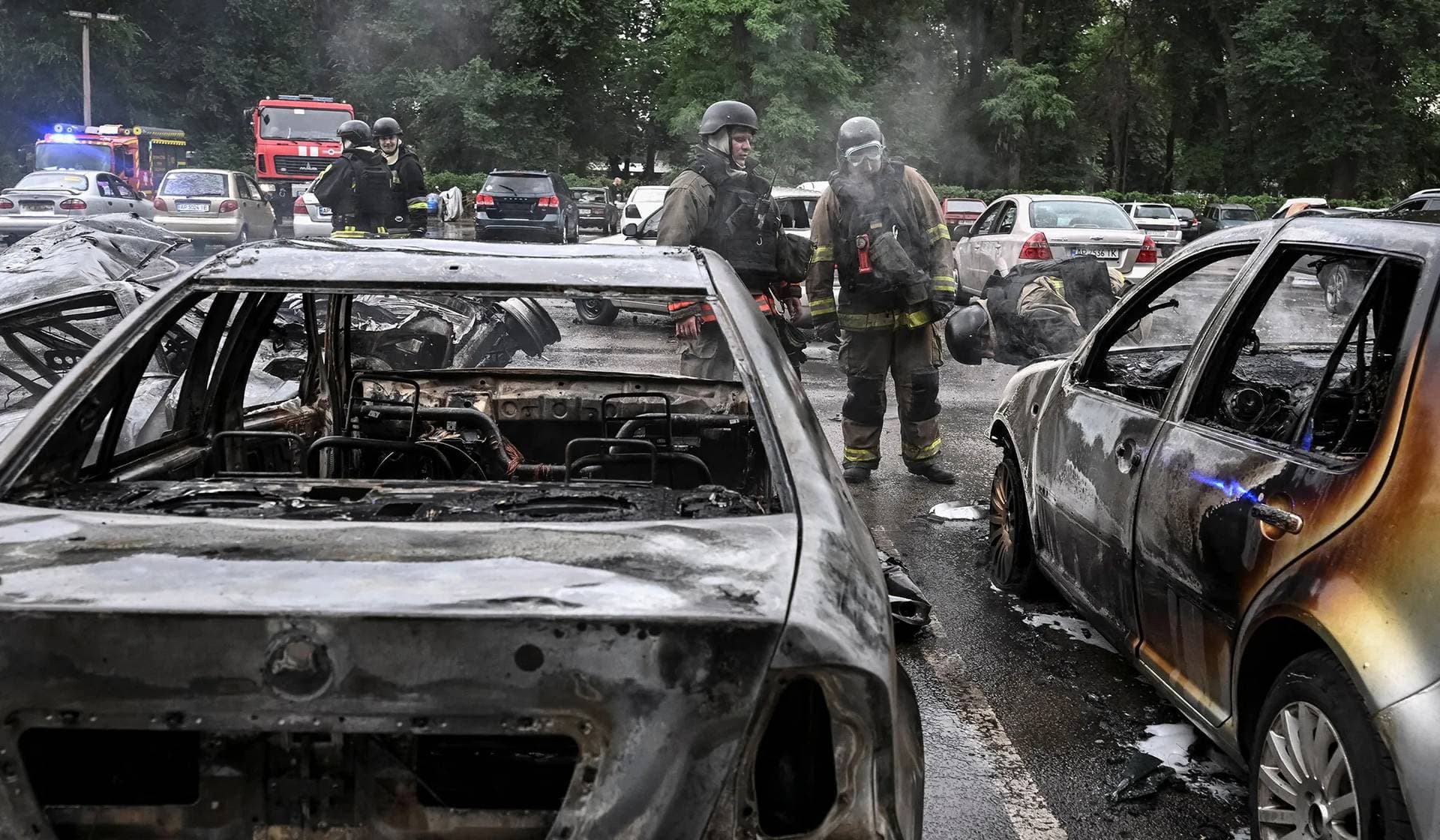 Rescuers work near charred vehicles at the parking lot hit by a Russian air strike in Zaporizhzhia