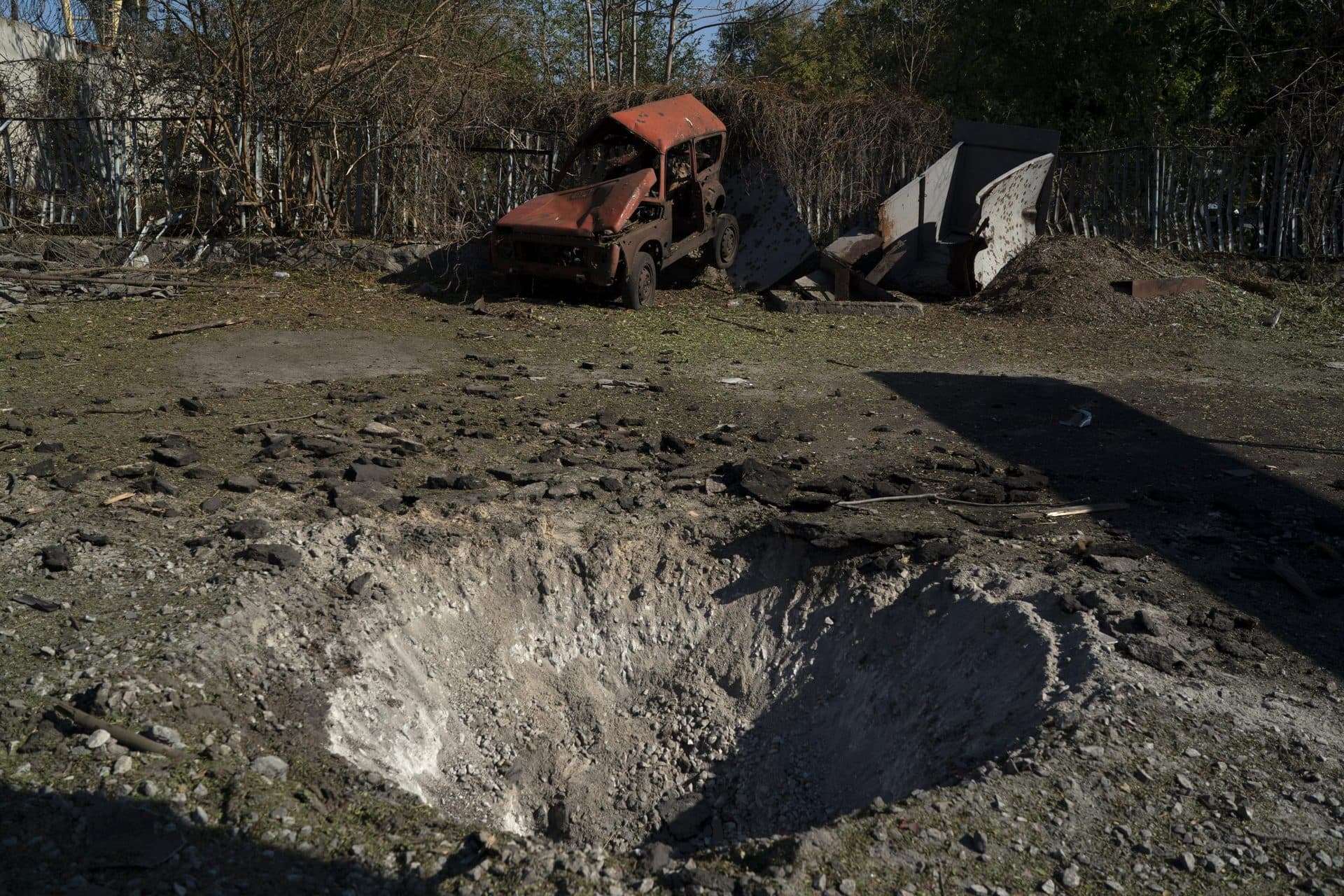 A destroyed car is seen next to a crater created by an explosion after a Russian attack in Zaporizhzhia