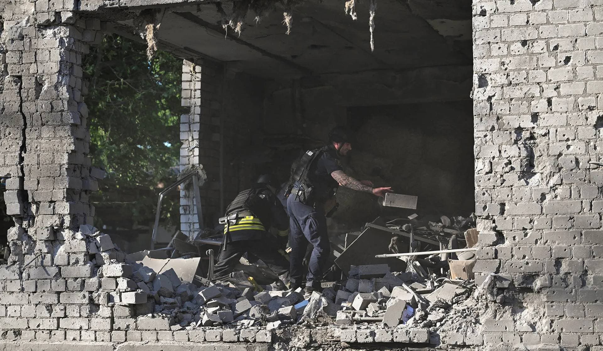 A police officer and a rescuer remove debris at the site of an administrative building that was hit by a Russian airstrike in Zaporizhzhia
