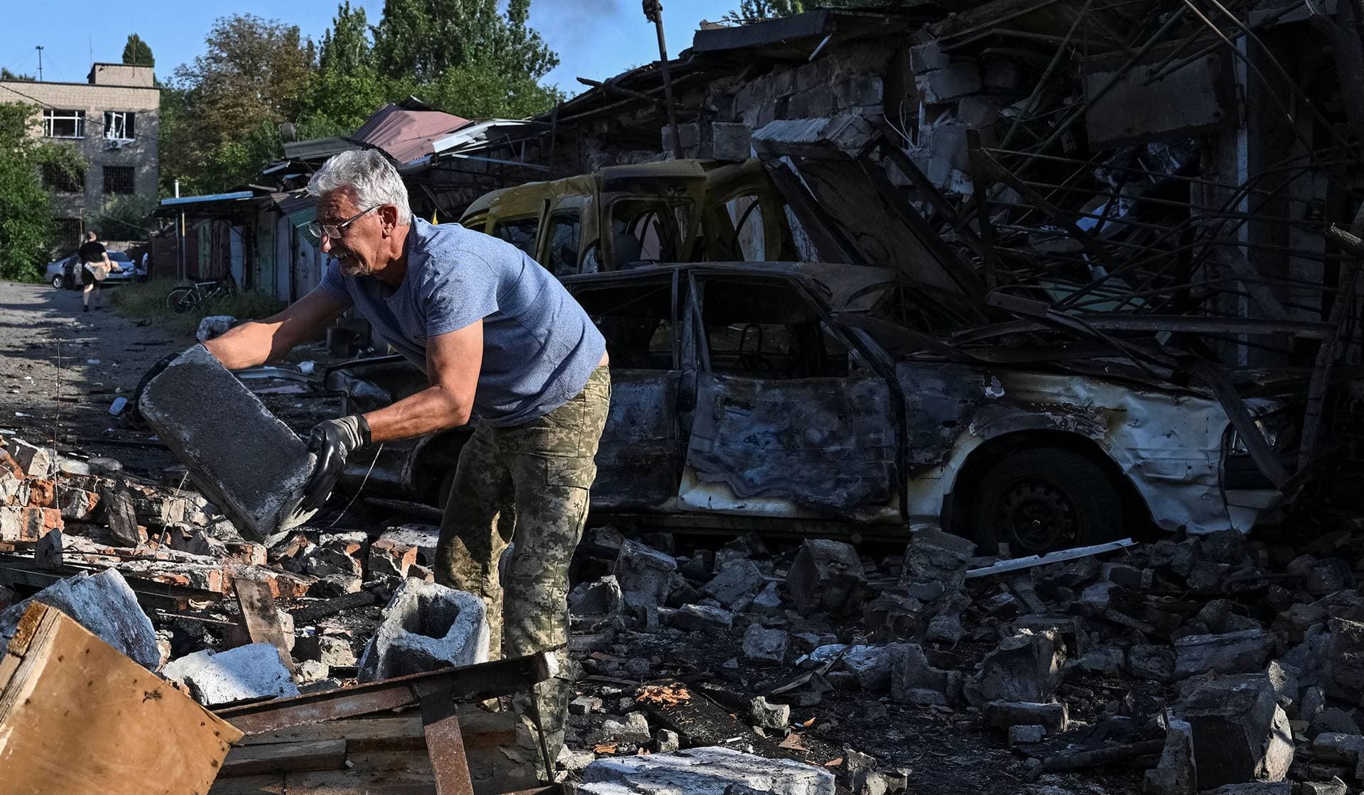 A resident clear debris at the site of a Russian missile and air strike in Zaporizhzhia