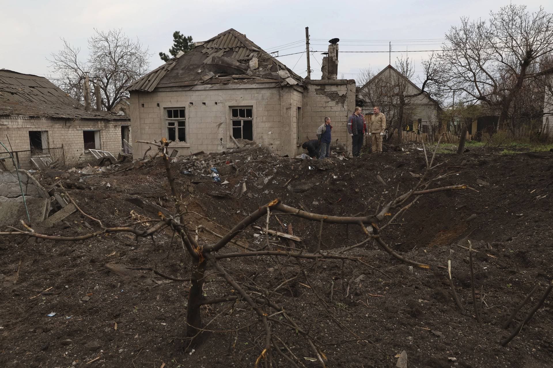 Local residents stand near a crater left by a Russian missile in Zaporizhzhia