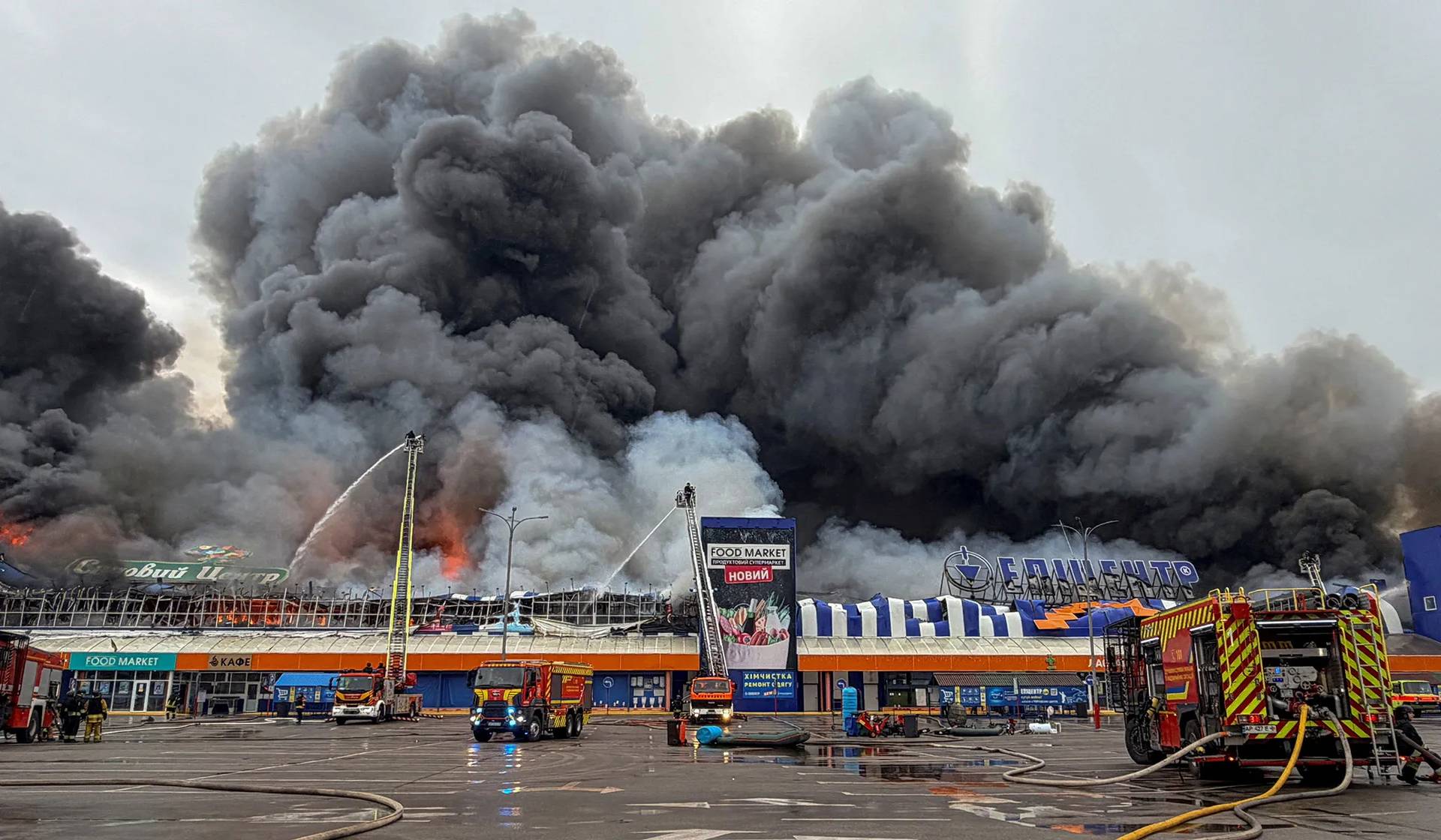 Firefighters work at the site of a household and construction item shopping mall as smoke and fire rise after Russian drone strikes in Zaporizhzhia