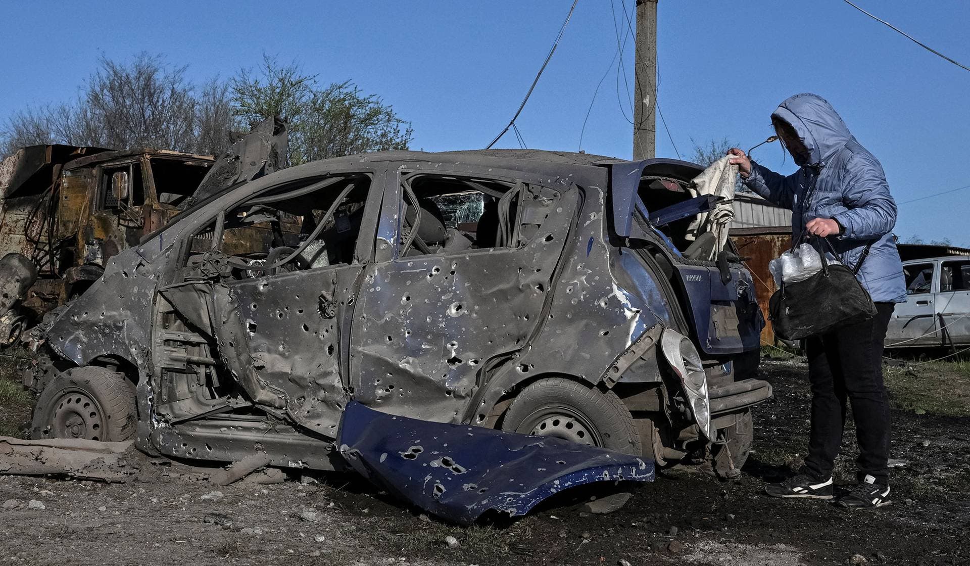 A resident inspects her destroyed car at the site of a Russian combined military strike in Zaporizhzhia