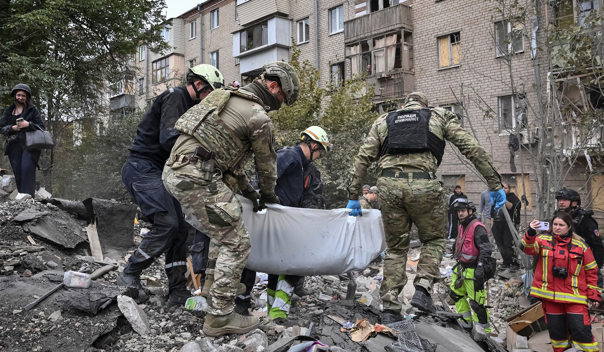 Rescuers carry the body of a killed person found under debris of an apartment building damaged during a Russian air strike in Zaporizhzhia