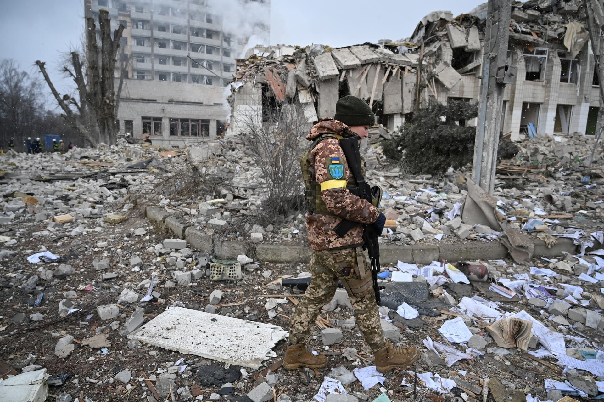 An Ukrainian trooper walks near a school building destroyed by shelling in Zhytomyr