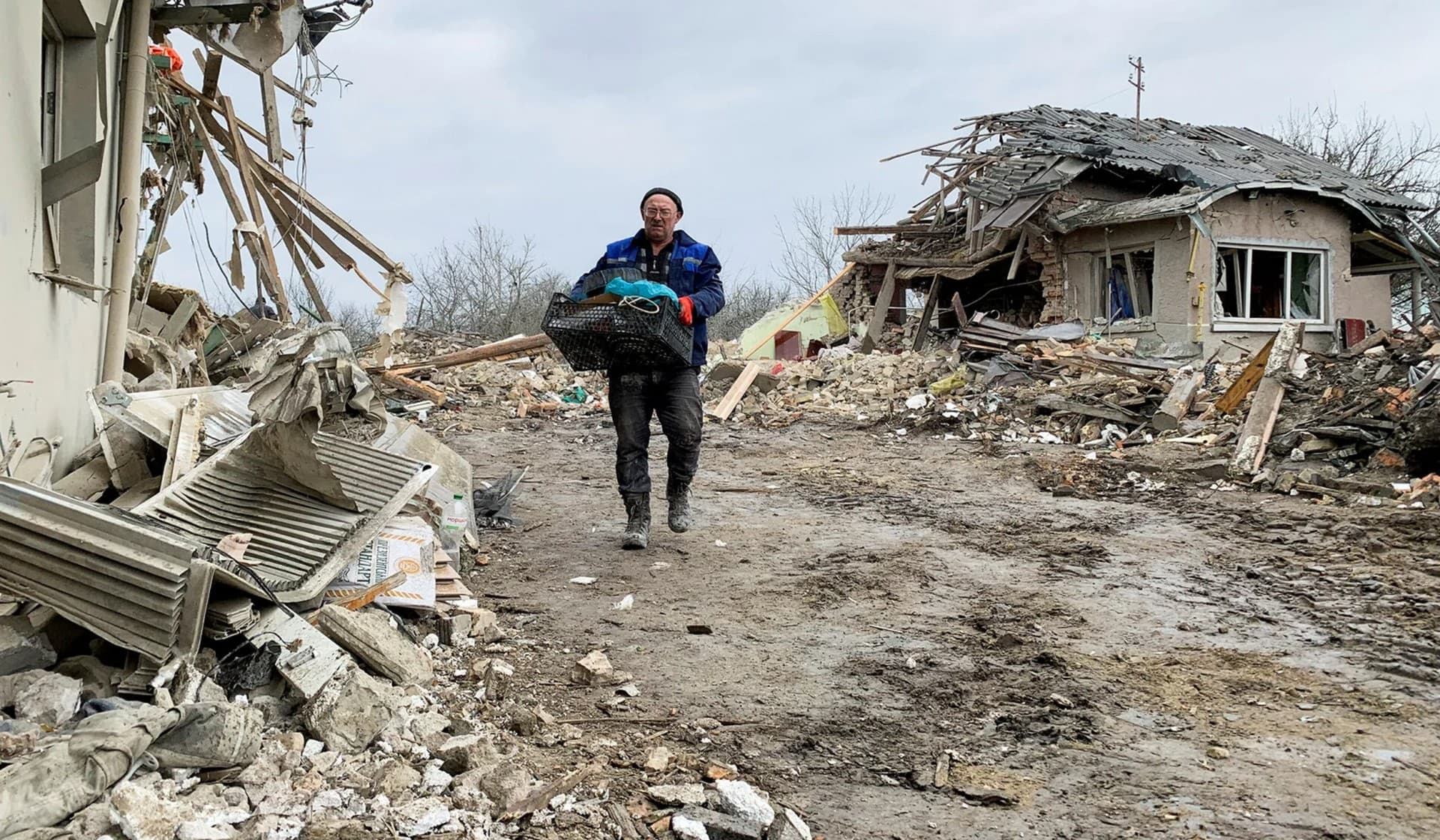 A local resident walks among the remains of residential buildings destroyed by a Russian missile strike near Zolochiv