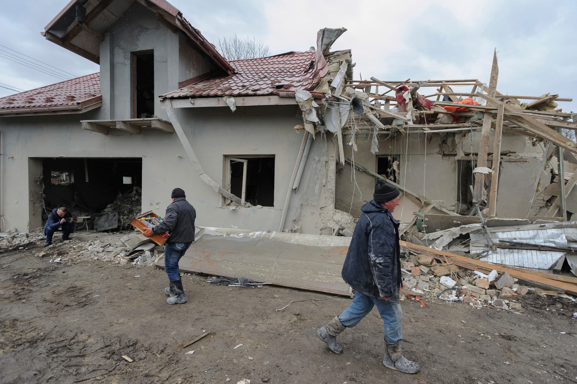 Villagers clear the rubble from a destroyed home in the village in Zolochevskiy